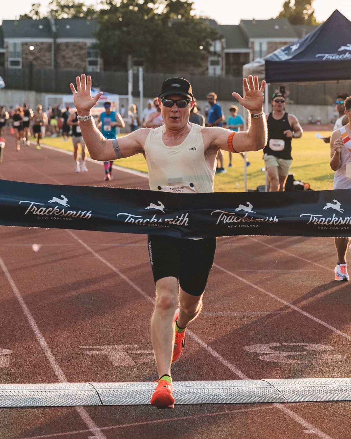 Scott Frye finishing a track race, arms raised, breaking the finish tape